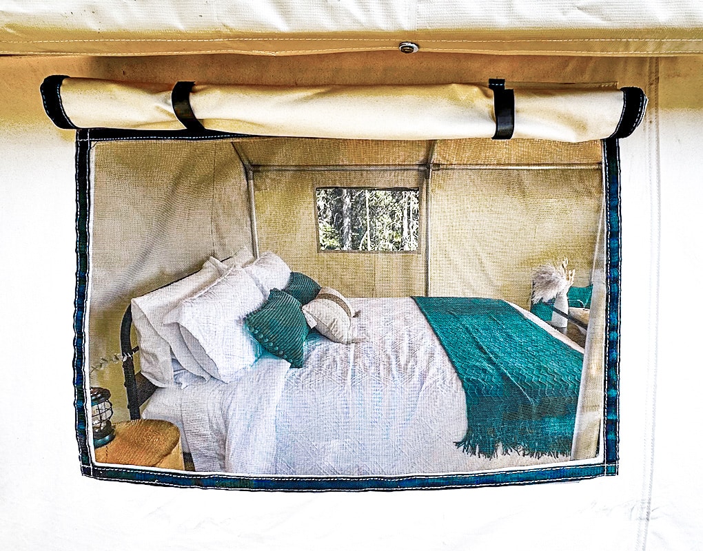 a bed with pillows and a lamp in a tent