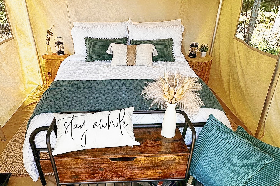 a bed with pillows and a table with a vase of flowers