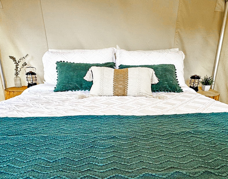 a bed with pillows and a green blanket