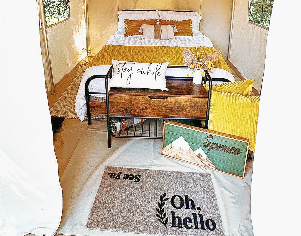 a bed with pillows and a table in a tent