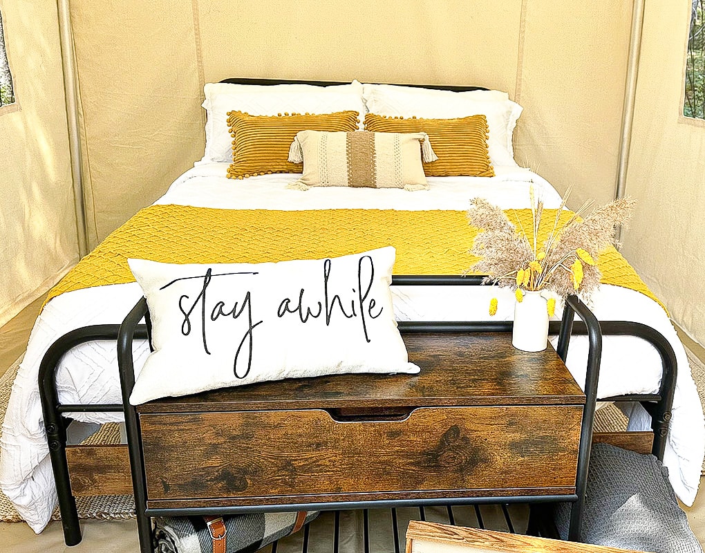 a bed with a yellow blanket and a wood table