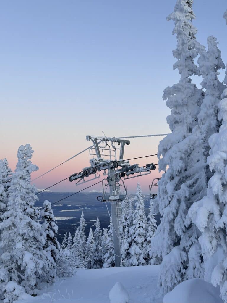 a ski lift with snow on trees
