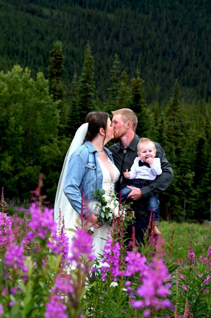 a man and woman kissing in a field of purple flowers